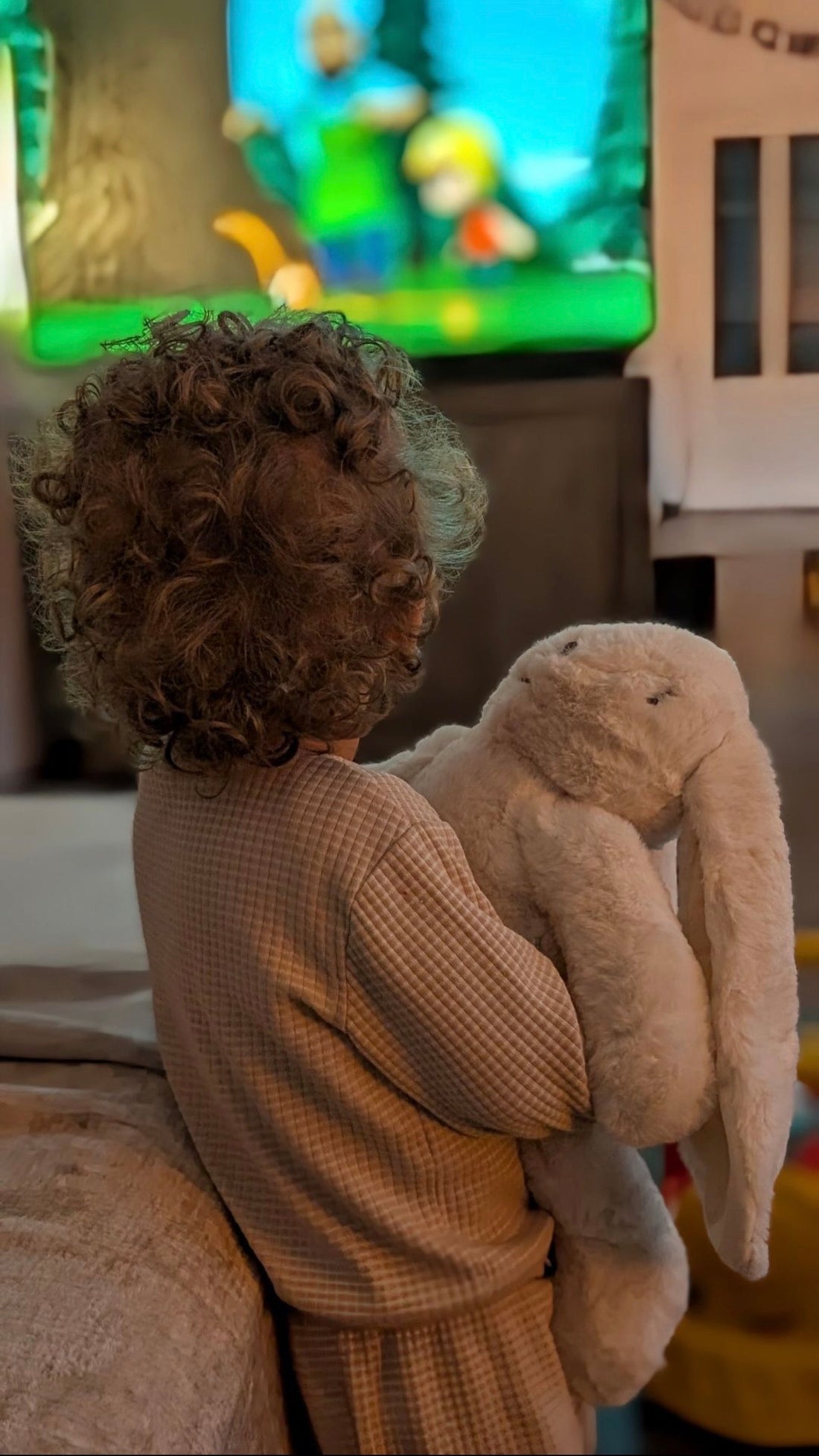Kind knuffelt de Konijn-verzwaringsknuffel op de bank na school