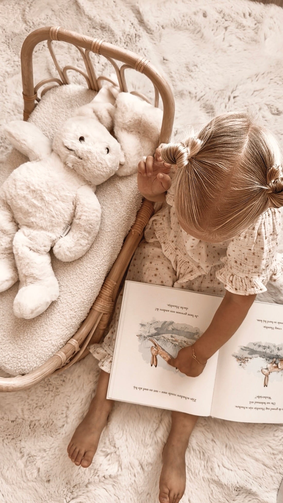 Meisje leest rustig een boek in bed naast de Konijn-verzwaringsknuffel tijdens de avondroutine