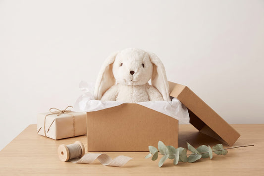 Verzwaringsknuffel Konijn in een open cadeaudoos met vloeipapier