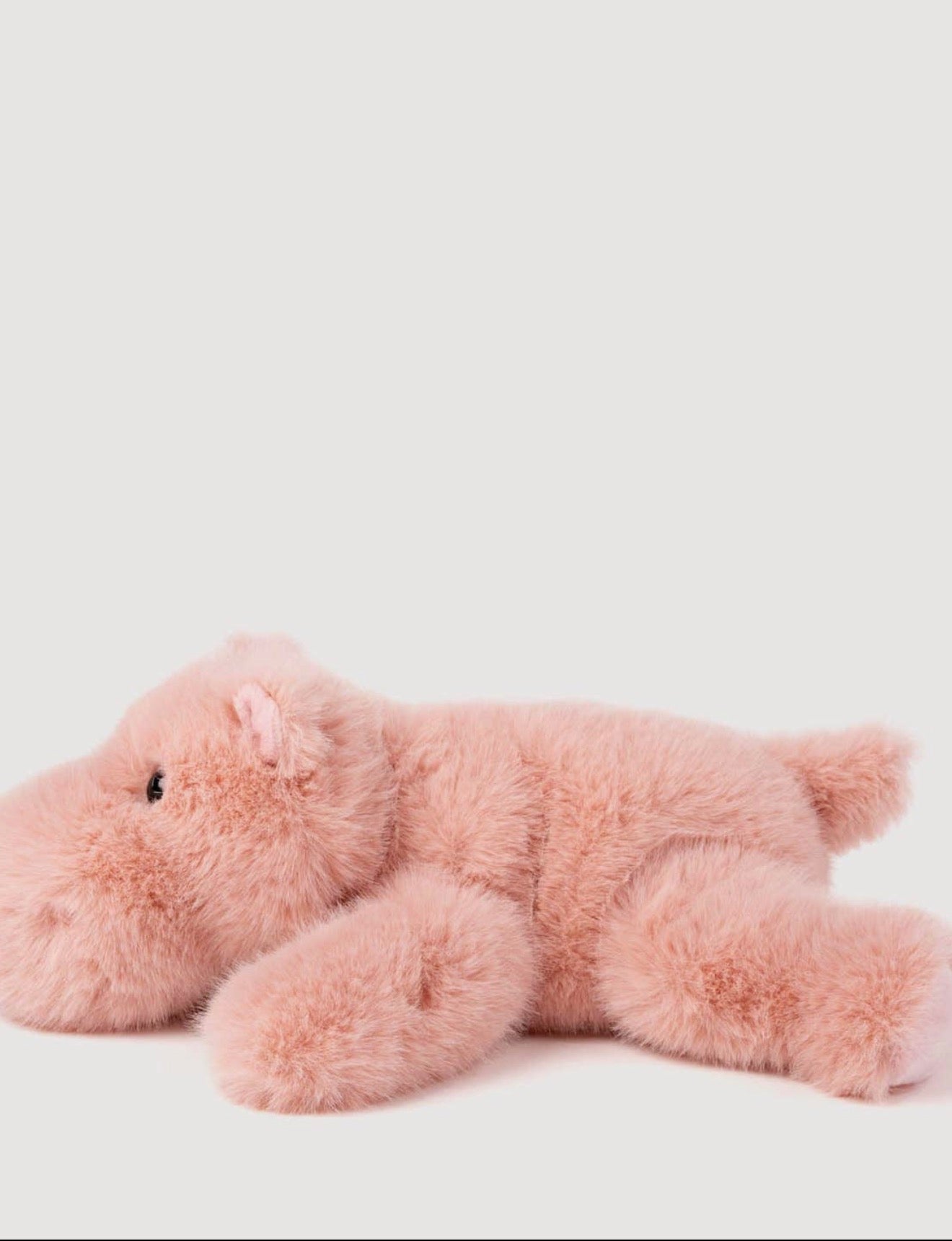 Zijaanzicht van de Pluche Nijlpaard knuffel liggend, met roze oor en kraaloogje