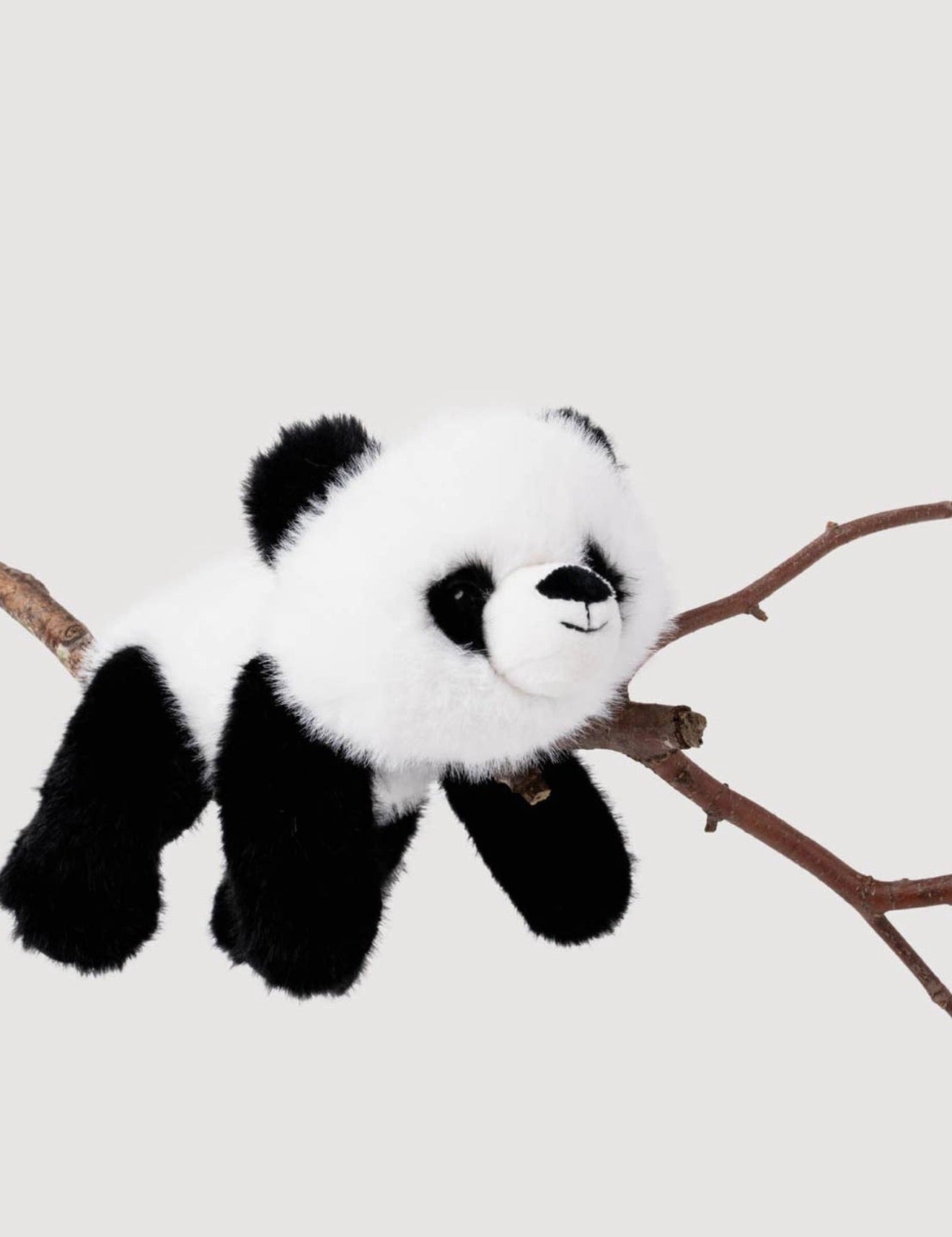 Pluche Panda knuffel hangend op een tak, met zwarte oogvlekken en zwarte neus