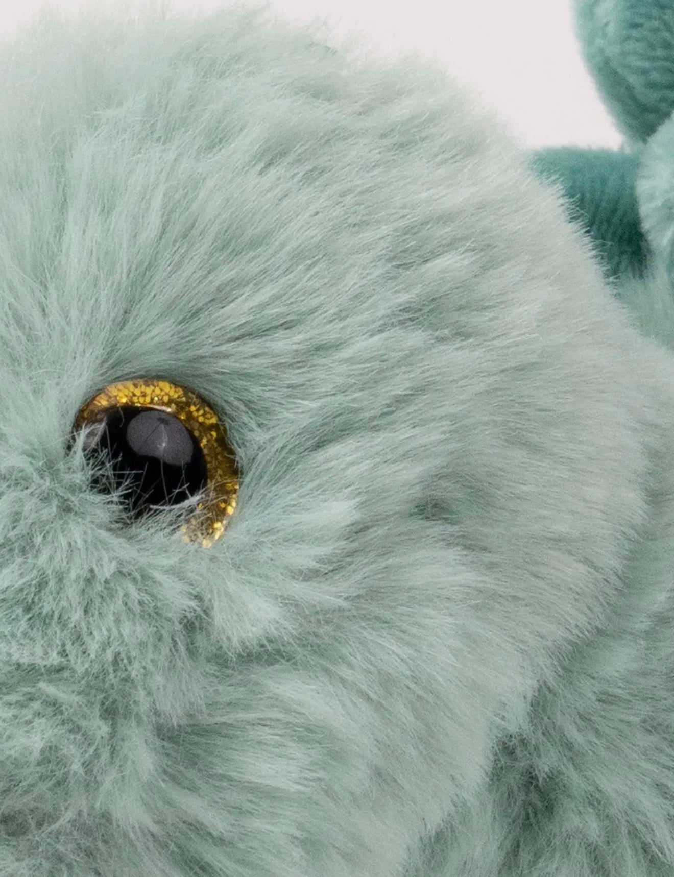 Detailfoto van het goudbruine oog en de zachte saliegroene vacht van de Pluche Stegosaurus knuffel